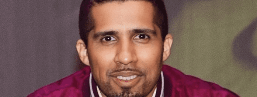 Man smiling in a maroon jacket.